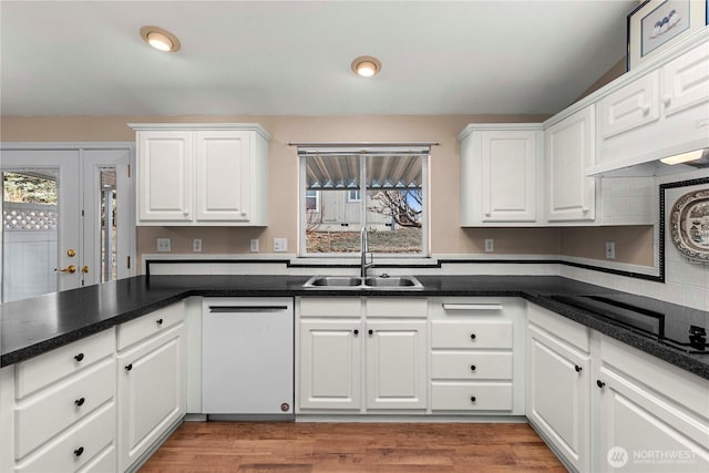 kitchen featuring a healthy amount of sunlight, white dishwasher, black electric stovetop, and a sink