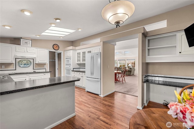 kitchen with dark countertops, white appliances, and white cabinets