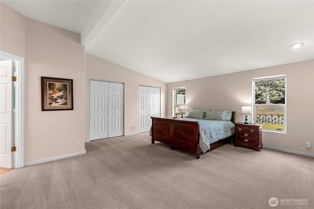 bedroom with carpet, lofted ceiling with beams, baseboards, and two closets