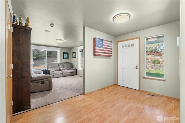 entrance foyer with baseboards, visible vents, and wood finished floors