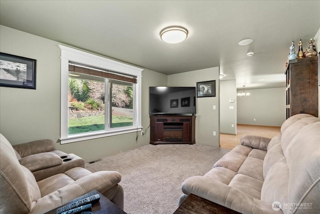 carpeted living room featuring a fireplace, visible vents, and a chandelier