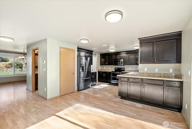 kitchen with a notable chandelier, appliances with stainless steel finishes, light wood-style floors, a sink, and baseboards