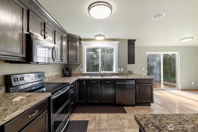 kitchen with a wealth of natural light, dark stone countertops, stainless steel appliances, and a sink