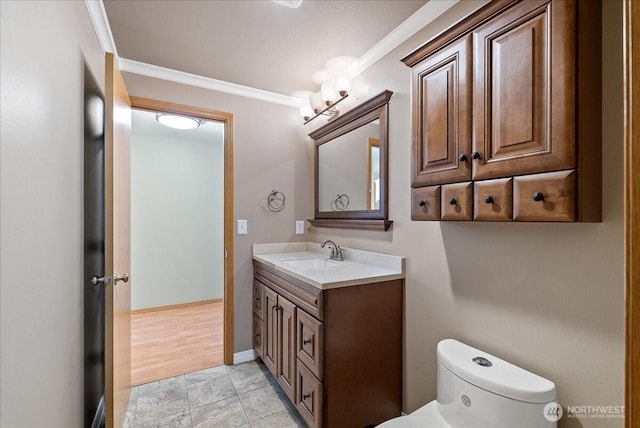 bathroom with toilet, baseboards, crown molding, and vanity