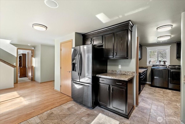 kitchen with baseboards, stainless steel fridge with ice dispenser, independent washer and dryer, light stone countertops, and light wood-style floors