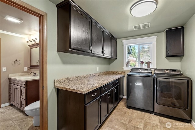 clothes washing area with visible vents, cabinet space, a sink, separate washer and dryer, and baseboards