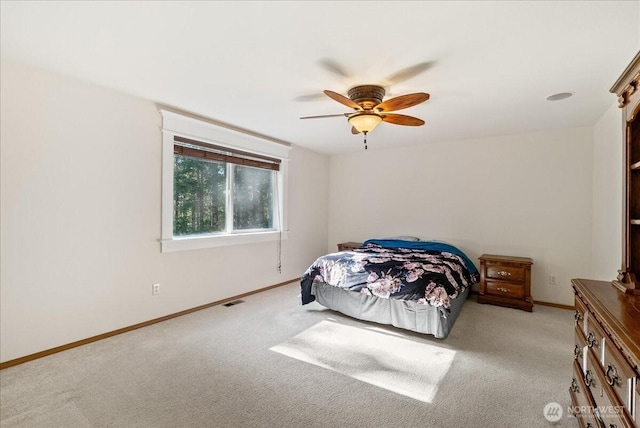 carpeted bedroom featuring a ceiling fan, visible vents, and baseboards