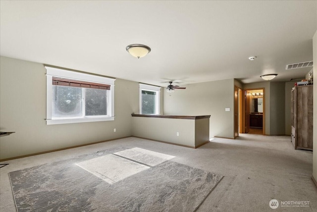 spare room with a ceiling fan, carpet flooring, visible vents, and baseboards