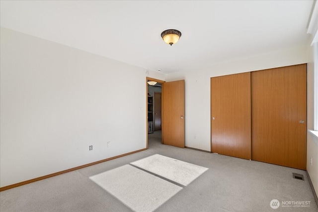 unfurnished bedroom featuring baseboards, carpet, visible vents, and a closet