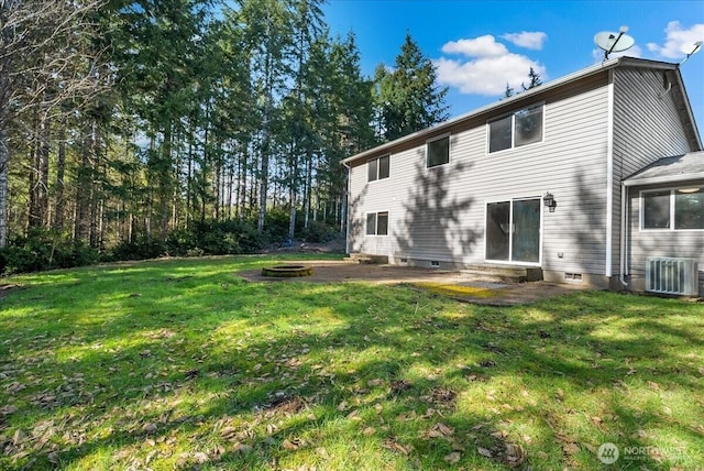 rear view of property with cooling unit, a yard, and a fire pit