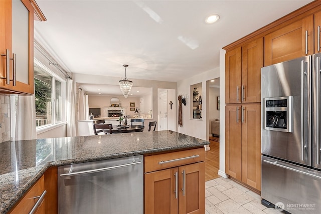 kitchen featuring dark stone counters, recessed lighting, brown cabinetry, and appliances with stainless steel finishes