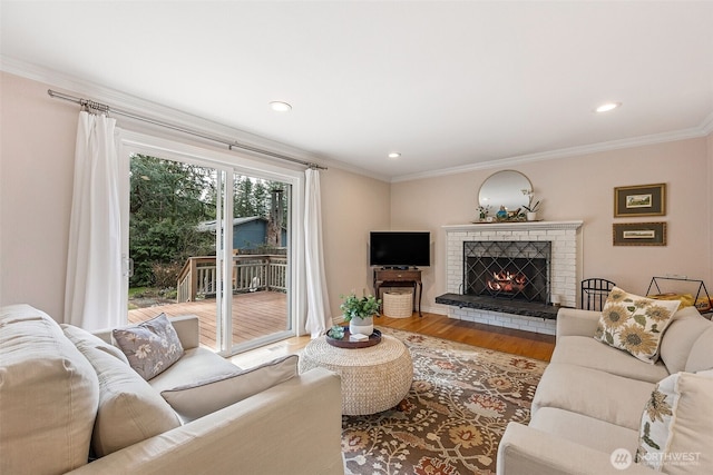 living room featuring crown molding, a brick fireplace, recessed lighting, and wood finished floors