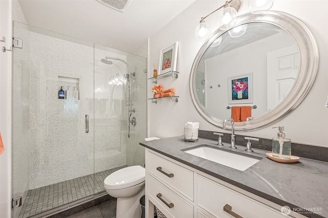 bathroom featuring visible vents, a shower stall, toilet, and vanity