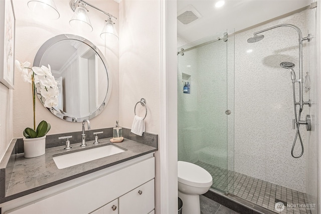 bathroom with vanity, a shower stall, toilet, and visible vents