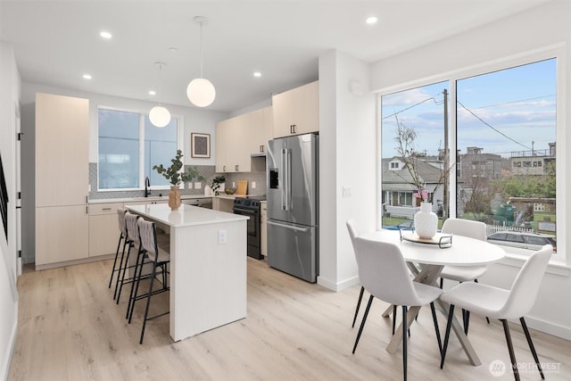 kitchen with stainless steel fridge, a breakfast bar, a center island, black / electric stove, and a sink