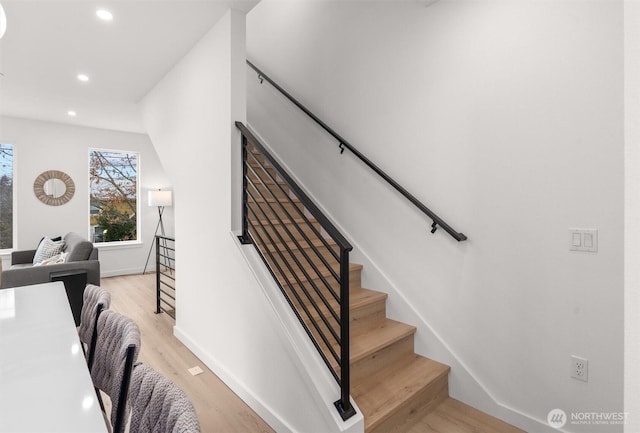 staircase with baseboards, wood finished floors, and recessed lighting