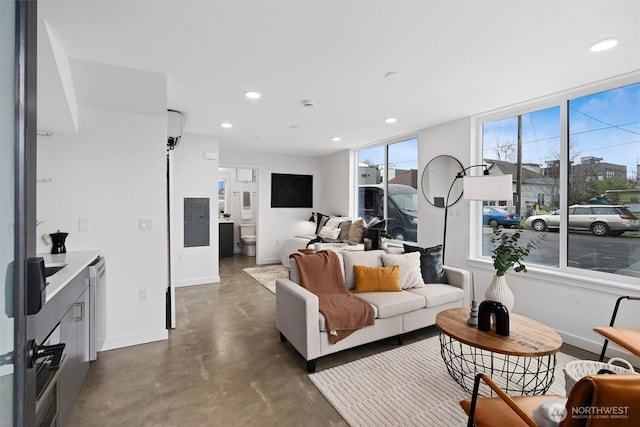 living room with concrete flooring, recessed lighting, electric panel, and baseboards