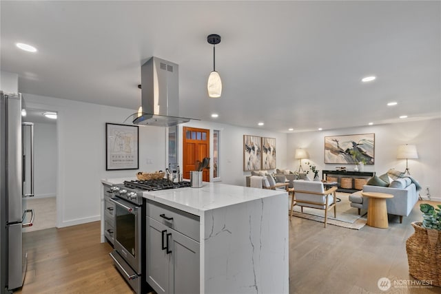 kitchen with open floor plan, appliances with stainless steel finishes, light stone countertops, and island range hood