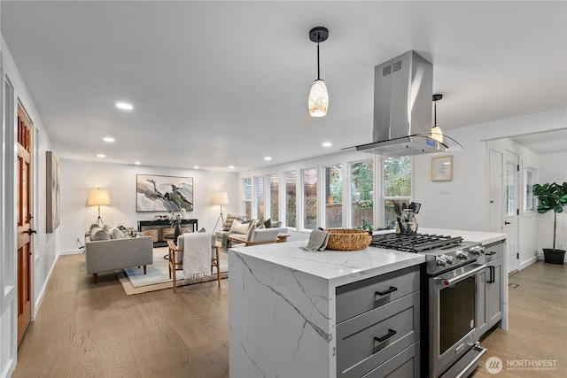 kitchen featuring light wood-style floors, gray cabinets, high end stove, and island range hood