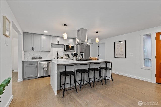 kitchen featuring stainless steel appliances, a sink, light countertops, gray cabinets, and island exhaust hood