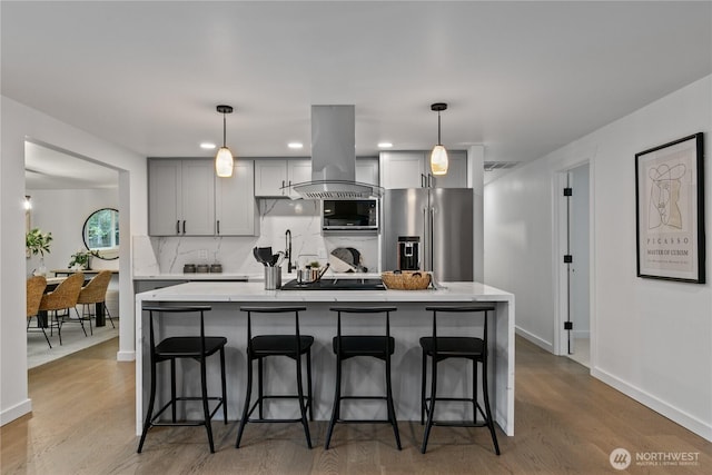 kitchen with built in microwave, island range hood, high end refrigerator, light wood-style floors, and decorative backsplash