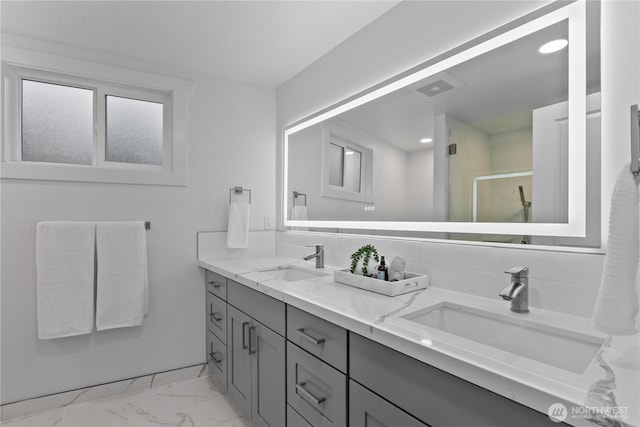 full bath featuring marble finish floor, a sink, backsplash, and double vanity