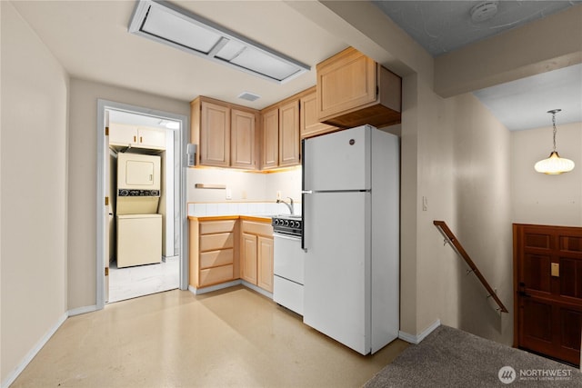 kitchen with pendant lighting, tile countertops, stacked washer / drying machine, white appliances, and baseboards