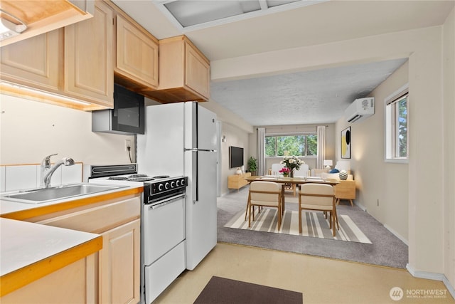 kitchen with electric stove, light countertops, light brown cabinetry, an AC wall unit, and a sink