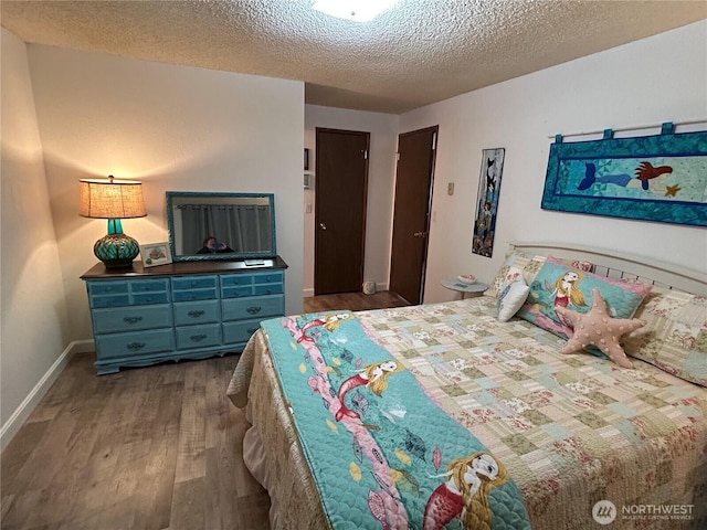 bedroom featuring a textured ceiling, baseboards, and wood finished floors