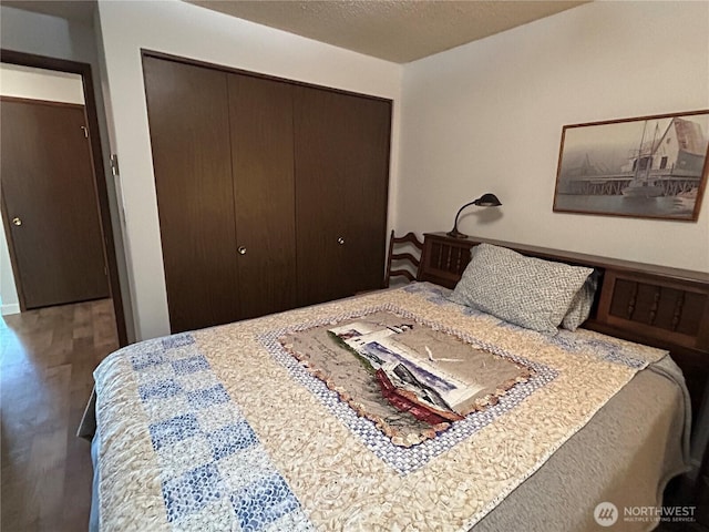 bedroom with a textured ceiling, a closet, and wood finished floors