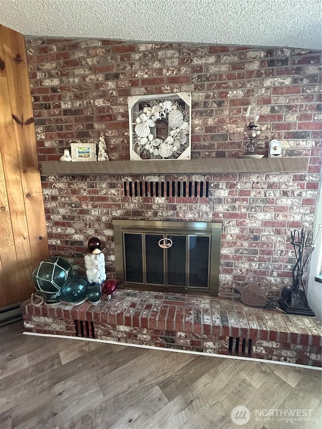 interior details featuring a textured ceiling, a fireplace, and wood finished floors