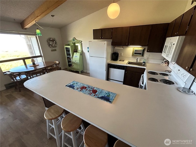 kitchen with dark brown cabinetry, a peninsula, white appliances, a sink, and light countertops