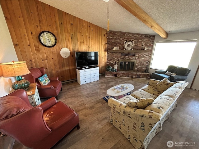 living area with beamed ceiling, wood finished floors, a textured ceiling, wood walls, and a brick fireplace