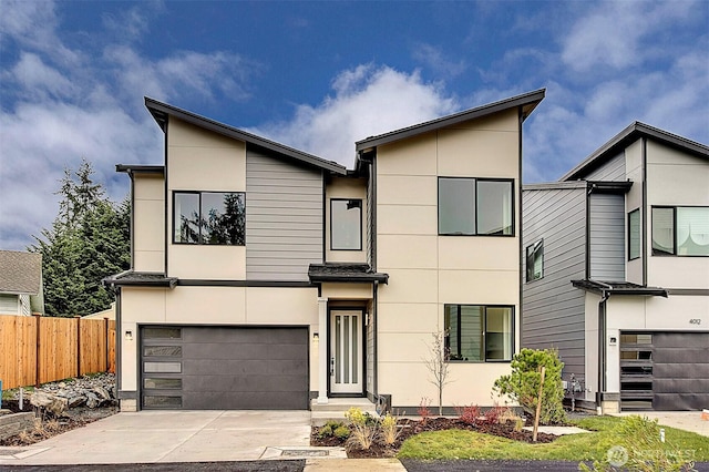 modern home featuring concrete driveway, fence, a garage, and stucco siding