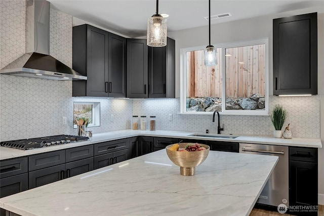 kitchen featuring visible vents, light stone countertops, stainless steel appliances, wall chimney exhaust hood, and a sink