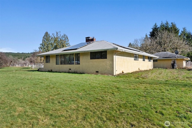 view of home's exterior with a yard, crawl space, roof mounted solar panels, stucco siding, and a chimney