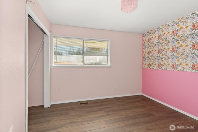 unfurnished room with visible vents, baseboards, and wood finished floors