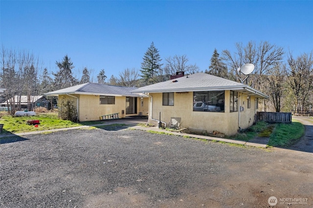 view of front of home with a chimney, fence, and stucco siding