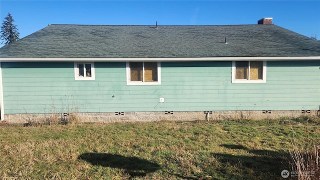 view of side of property featuring a yard, a shingled roof, crawl space, and a chimney