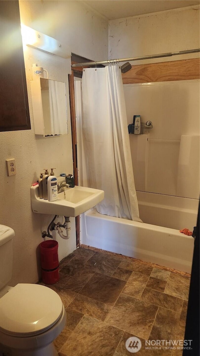 bathroom featuring toilet, shower / tub combo, and stone finish flooring