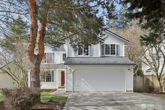 traditional home featuring an attached garage, fence, driveway, and a shingled roof