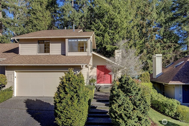 view of front of property with a garage, a chimney, a shingled roof, and driveway