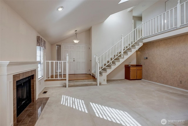 interior space featuring high vaulted ceiling, carpet flooring, visible vents, and stairs