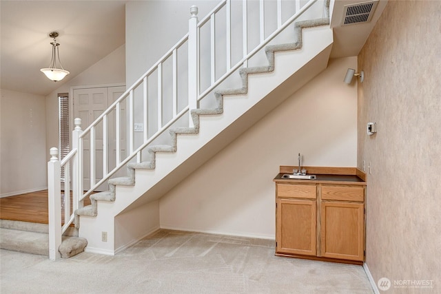 stairway with high vaulted ceiling, carpet flooring, visible vents, and baseboards