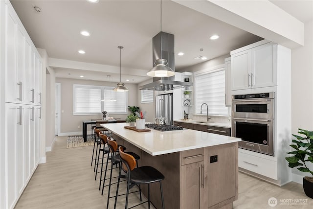 kitchen featuring a kitchen island, appliances with stainless steel finishes, a breakfast bar, white cabinetry, and a sink