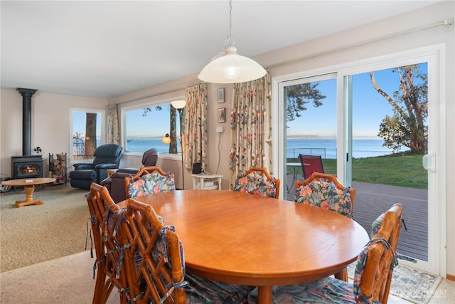 carpeted dining area with a wood stove and a water view