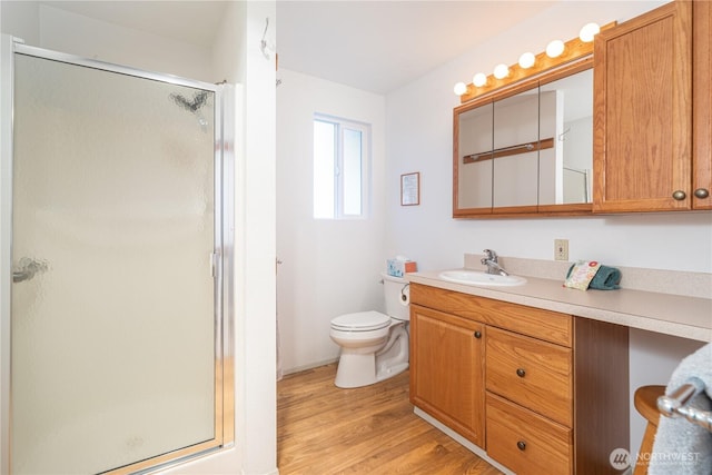 bathroom featuring toilet, a shower stall, vanity, and wood finished floors