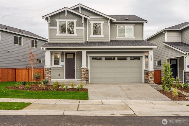 craftsman inspired home featuring an attached garage, fence, concrete driveway, stone siding, and board and batten siding