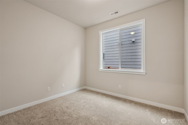 carpeted spare room featuring baseboards and visible vents
