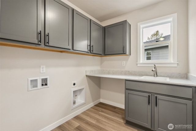 washroom with hookup for an electric dryer, a sink, baseboards, cabinet space, and washer hookup